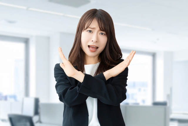 手でバツのポーズをして怒る女性